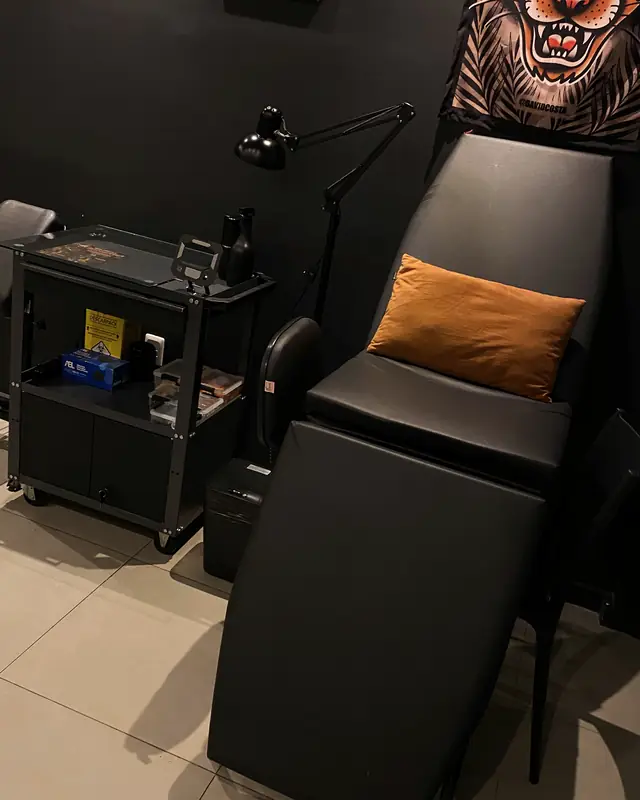 A maca de tatuagem, com a almofada laranja e a luminária